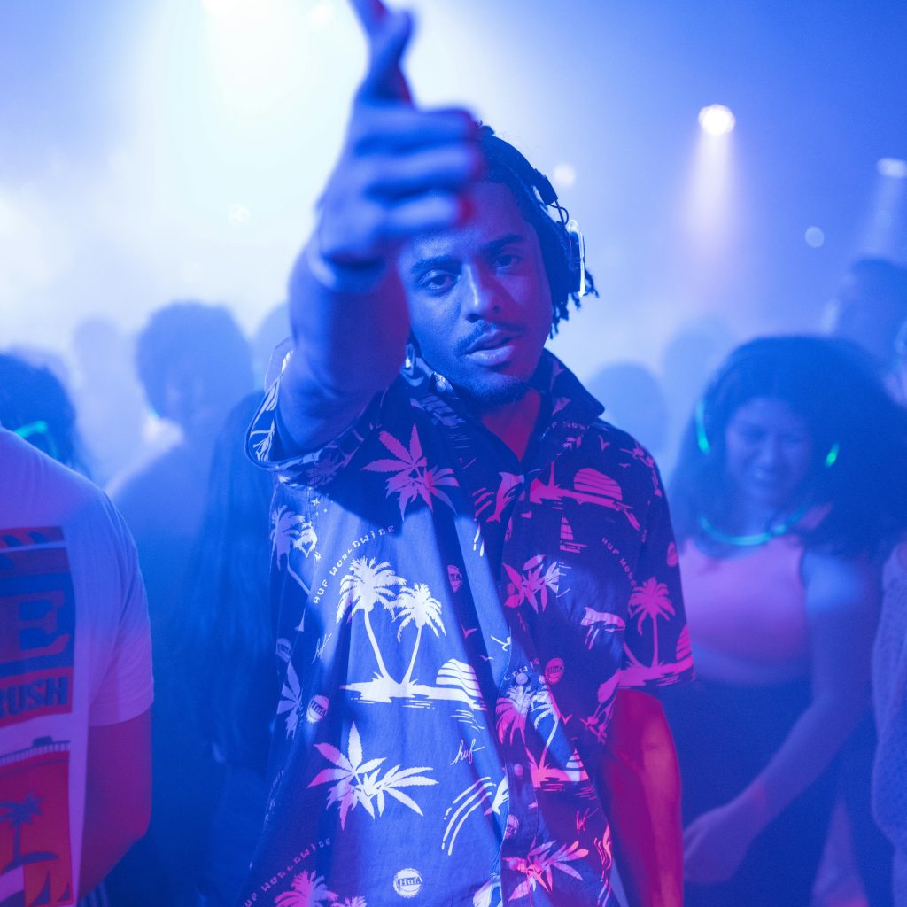 Our Team Vibrant nightclub scene with a lively partygoer and dancing crowd under colorful lights.